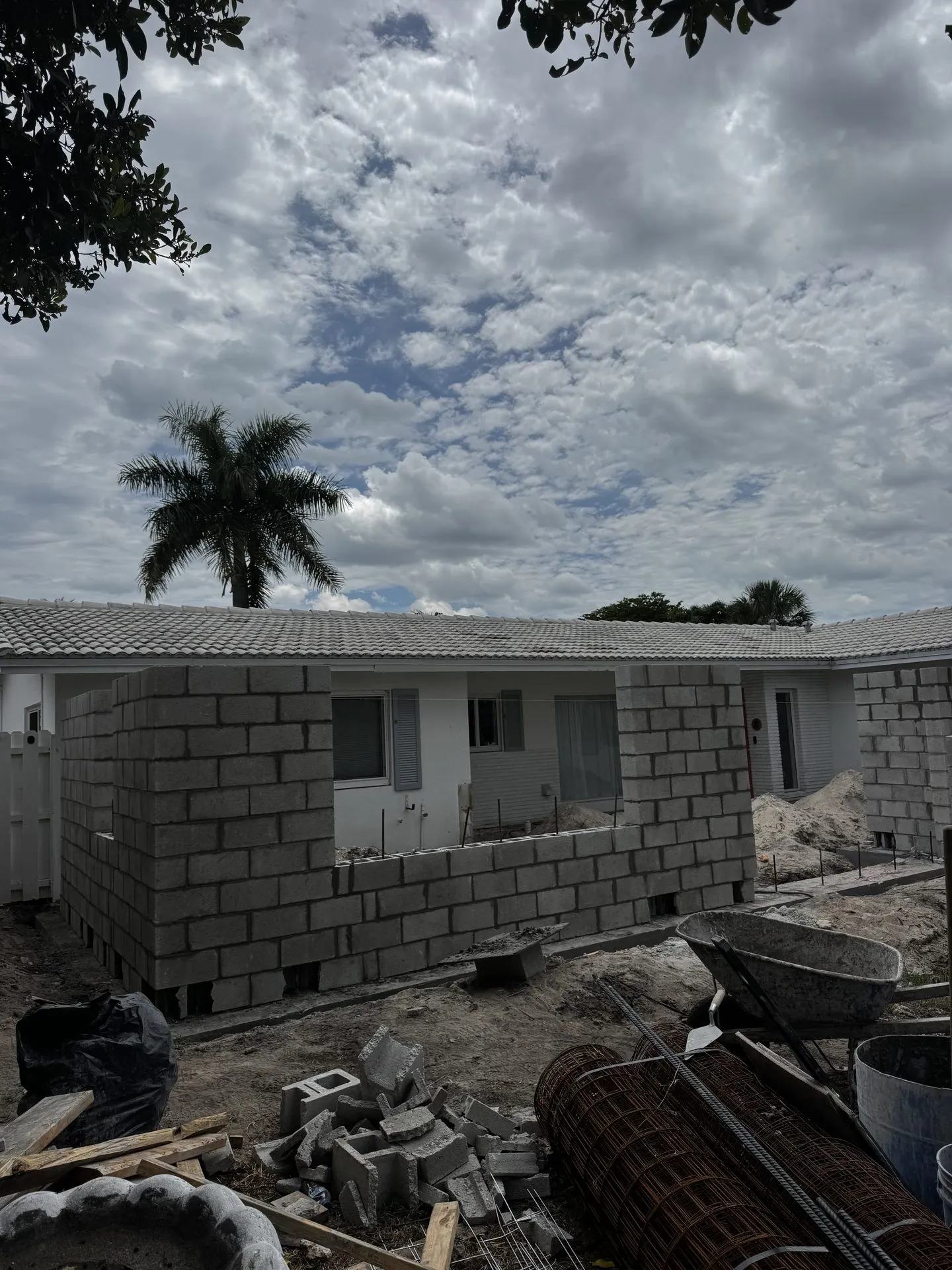 Concrete block walls of a new home addition going up behind a Miami house