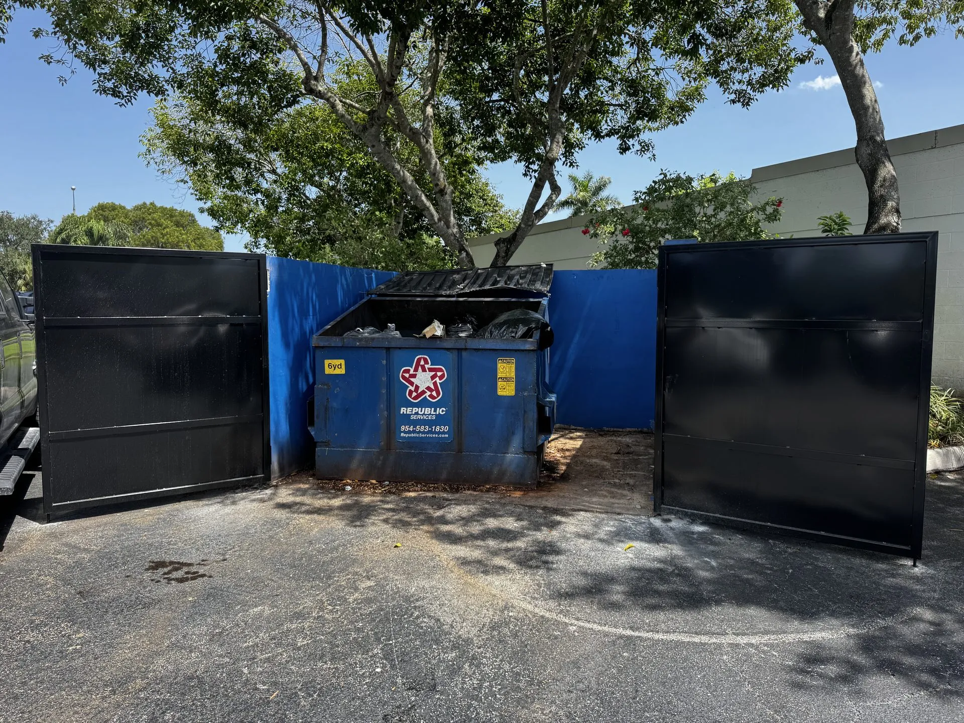 Open custom steel gate at a commercial dumpster enclosure