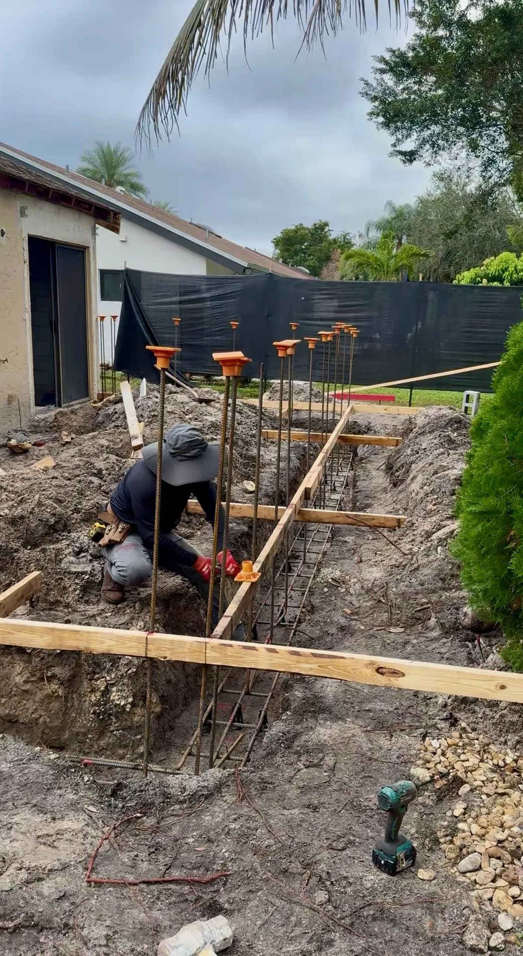 Worker setting rebar in a footing trench for a new foundation