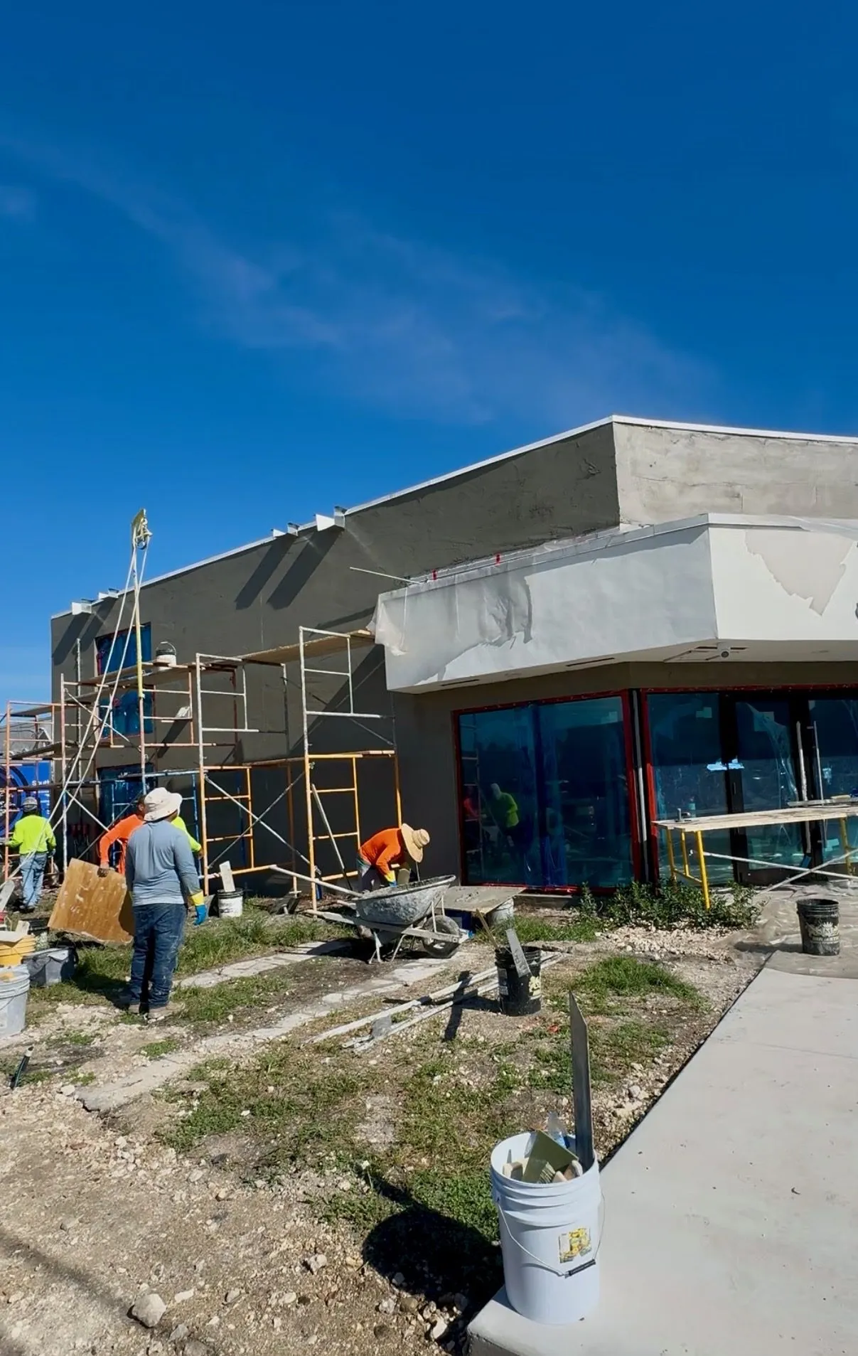 Stucco crew working from scaffolding on the exterior of a commercial building