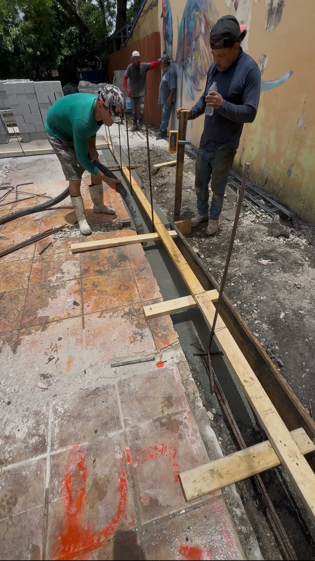 Crew forming and pouring a footing next to an existing concrete slab