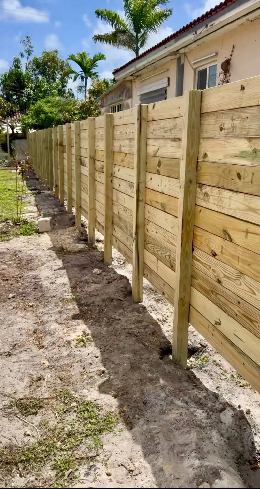Finished horizontal pressure-treated wood privacy fence along a residential yard