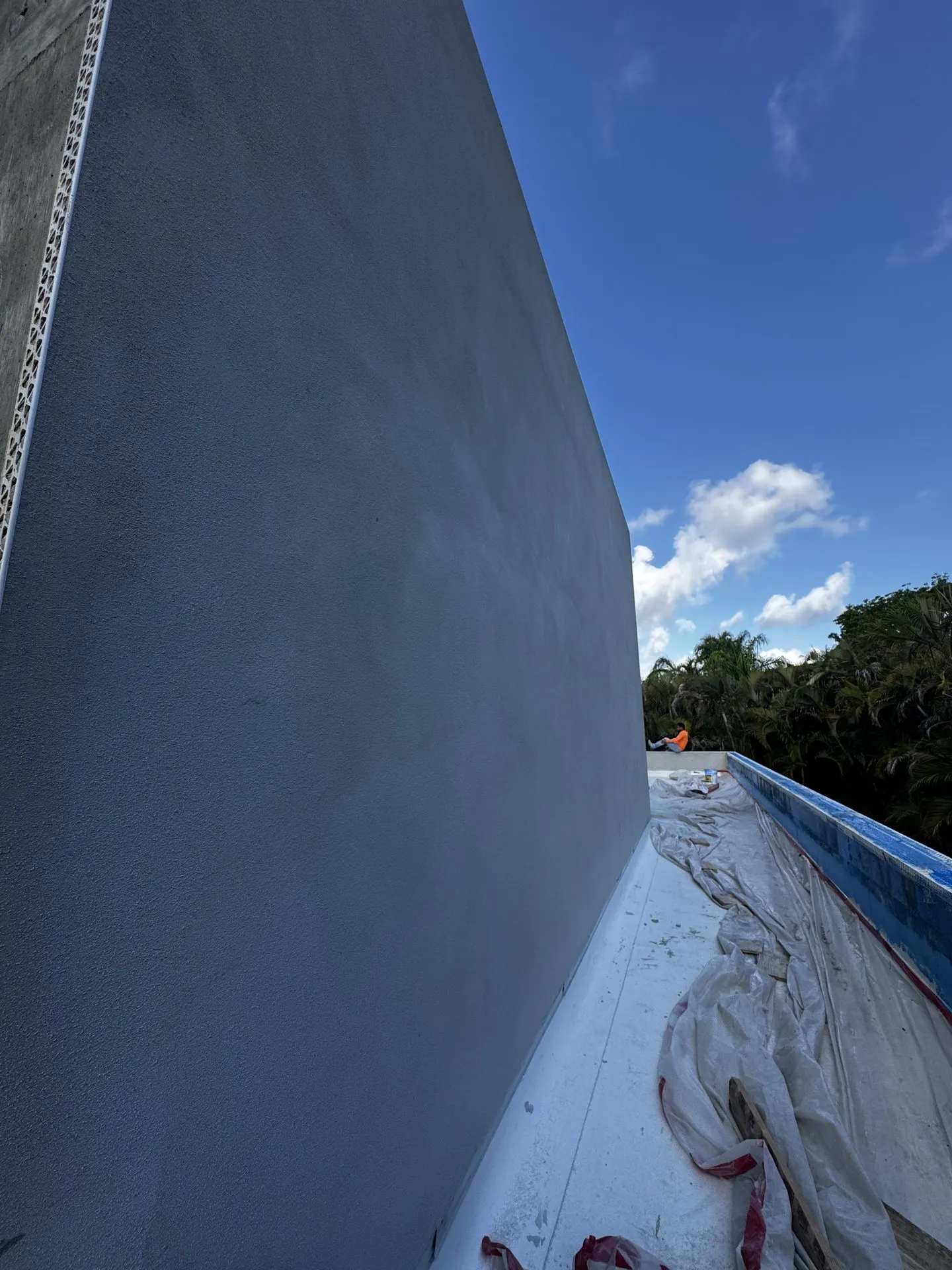 Smooth gray stucco finish on a tall exterior wall under a blue Florida sky