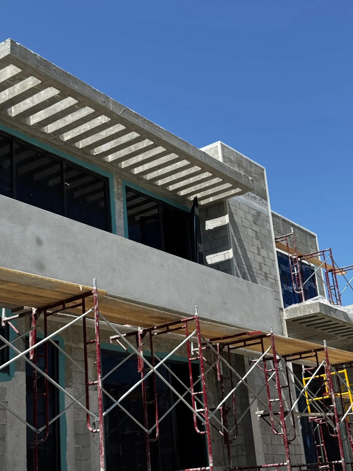 Concrete block building with scaffolding and an exposed concrete pergola