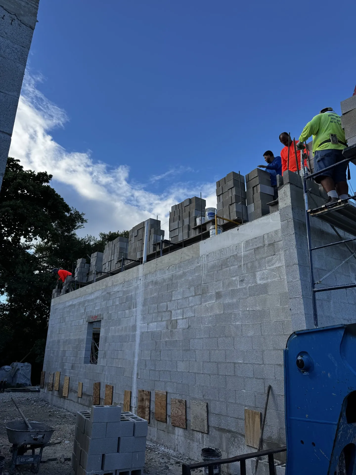Masonry crew building a block wall from scaffolding on a sunny day