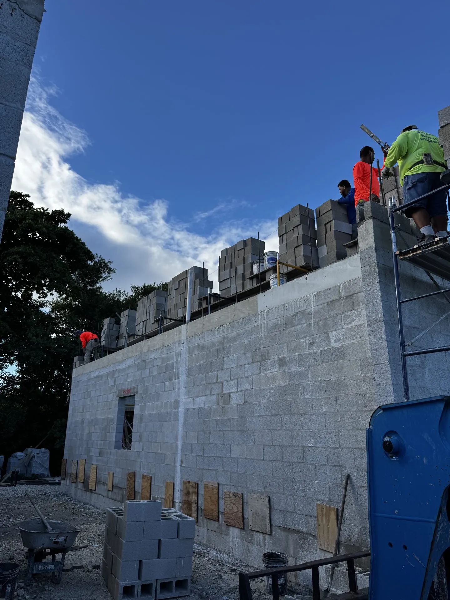 Masonry crew laying block along the upper course of a new wall