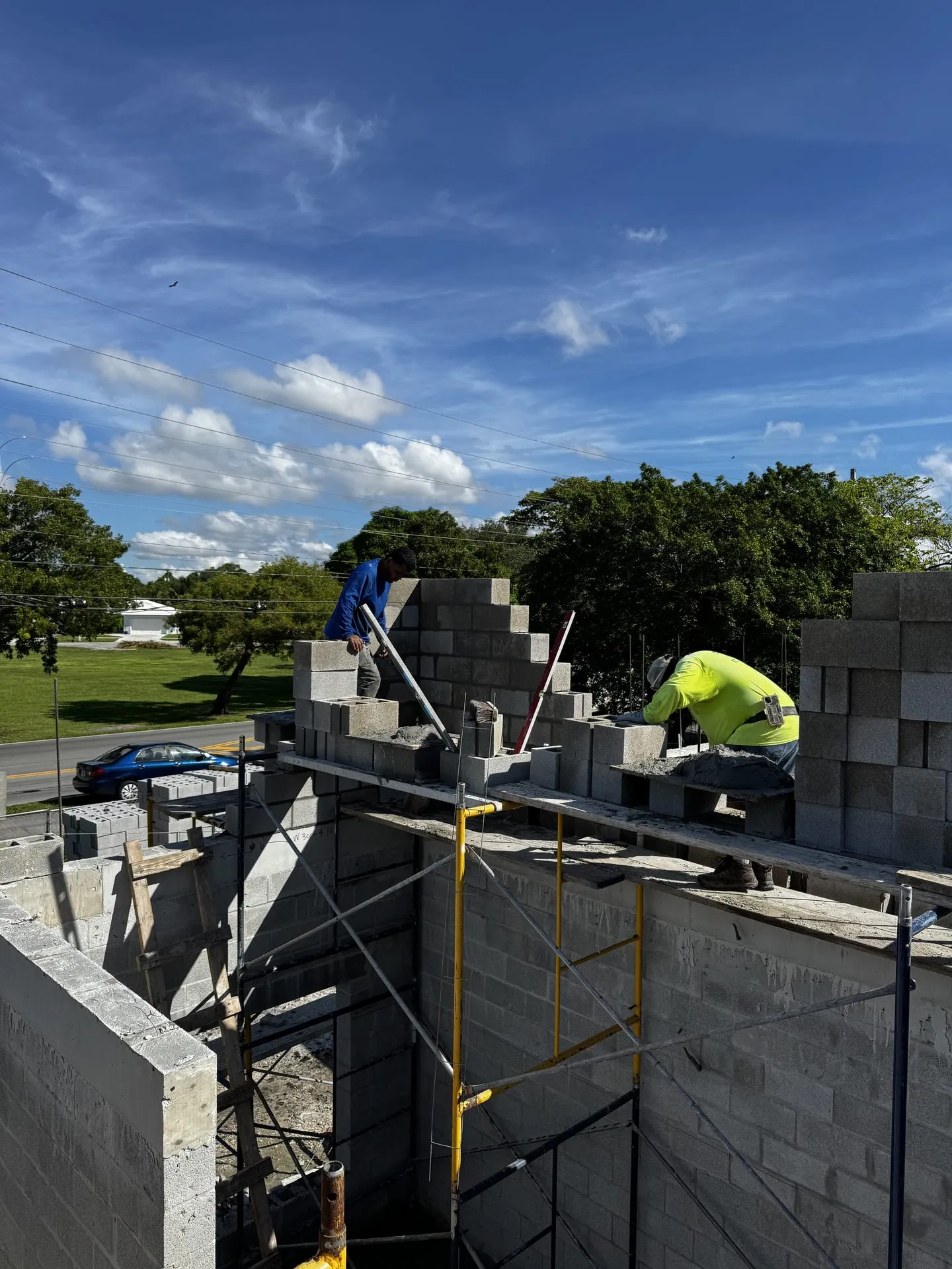 Crew stacking block on top of a finished concrete block wall