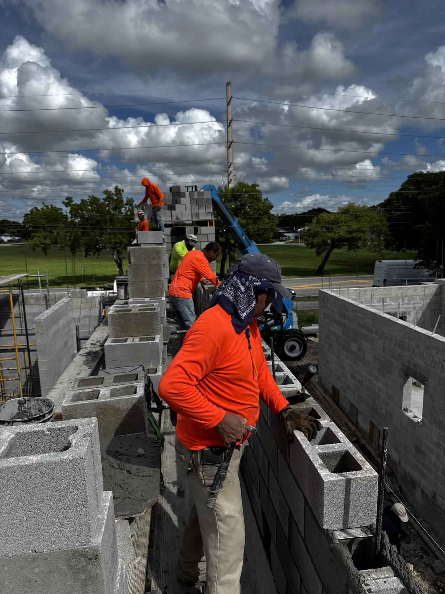 Masonry crew laying concrete block on a new structural wall in Miami