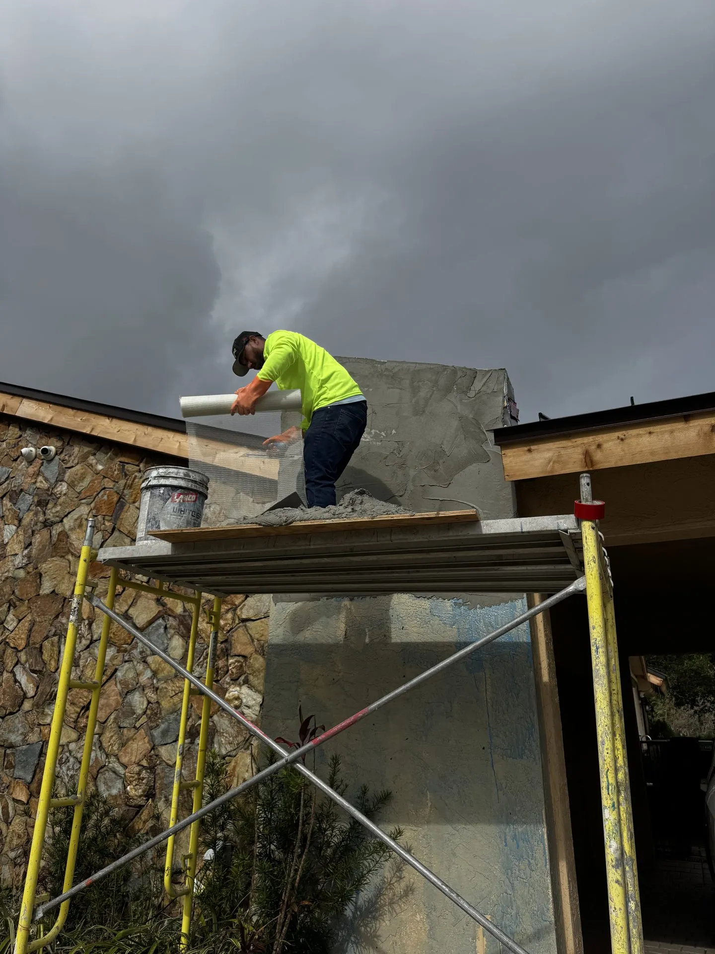 Stucco applied by hand from scaffolding on a new exterior wall