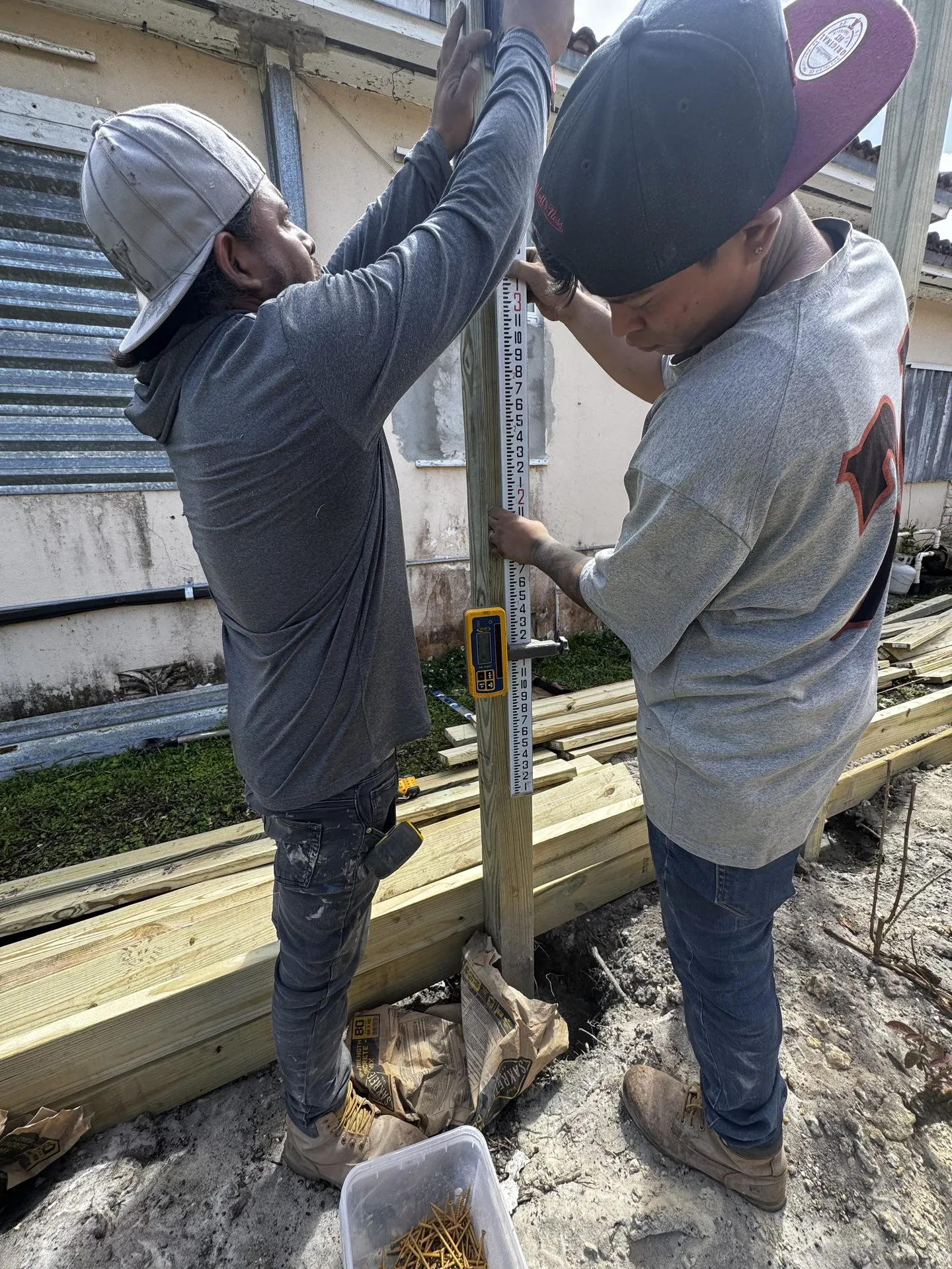 Two workers setting and leveling wood posts for a new fence