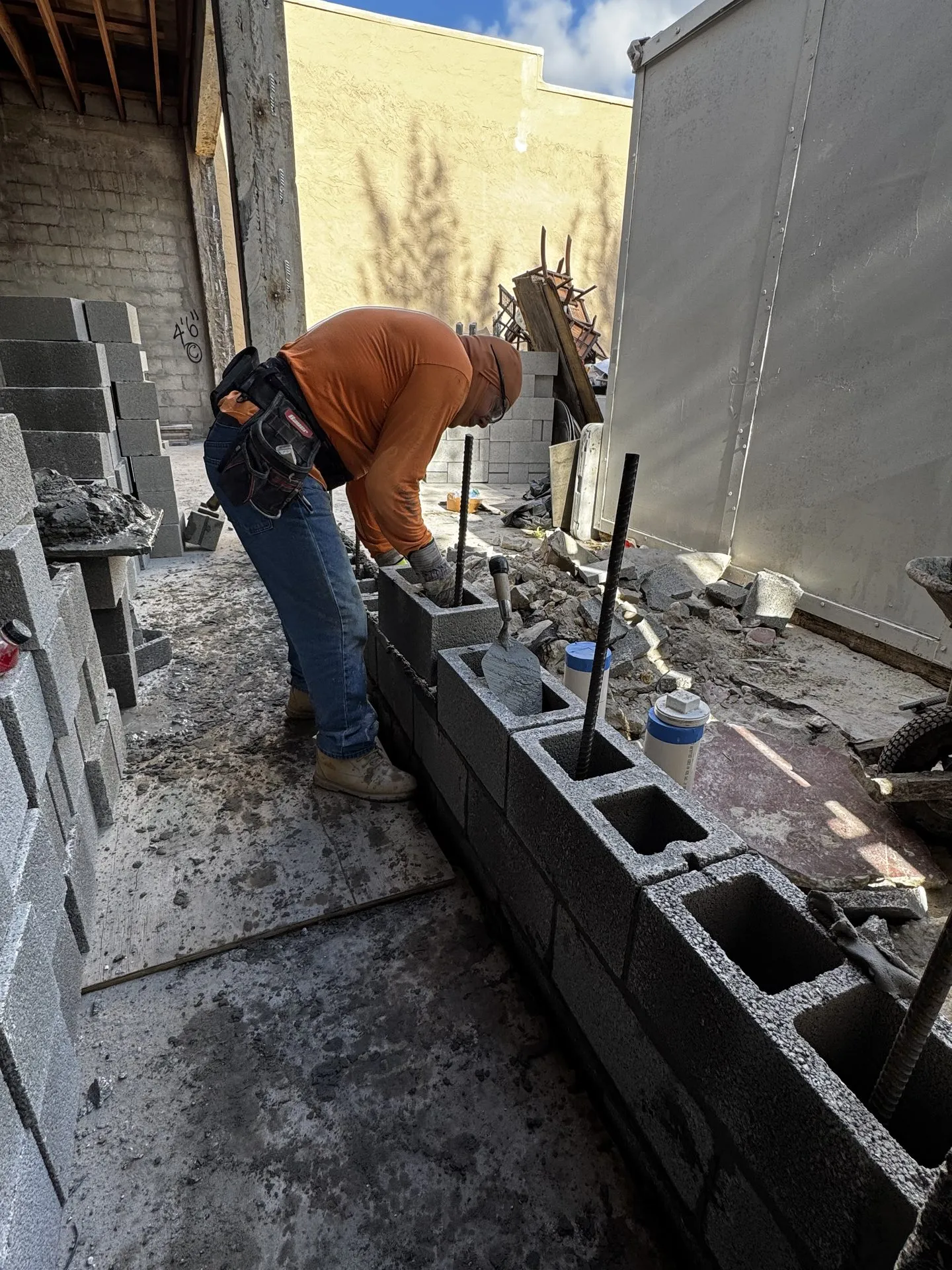 Mason laying and reinforcing concrete block cells with rebar