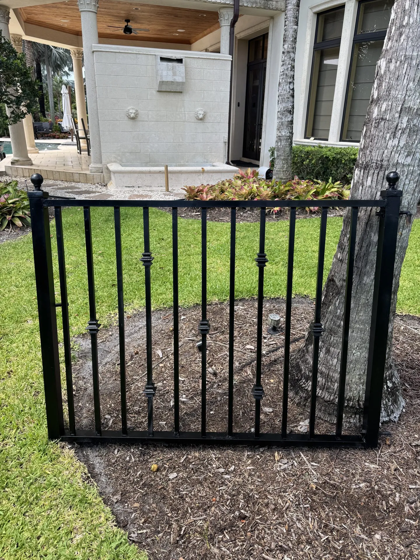Custom iron garden gate installed beside a Miami home