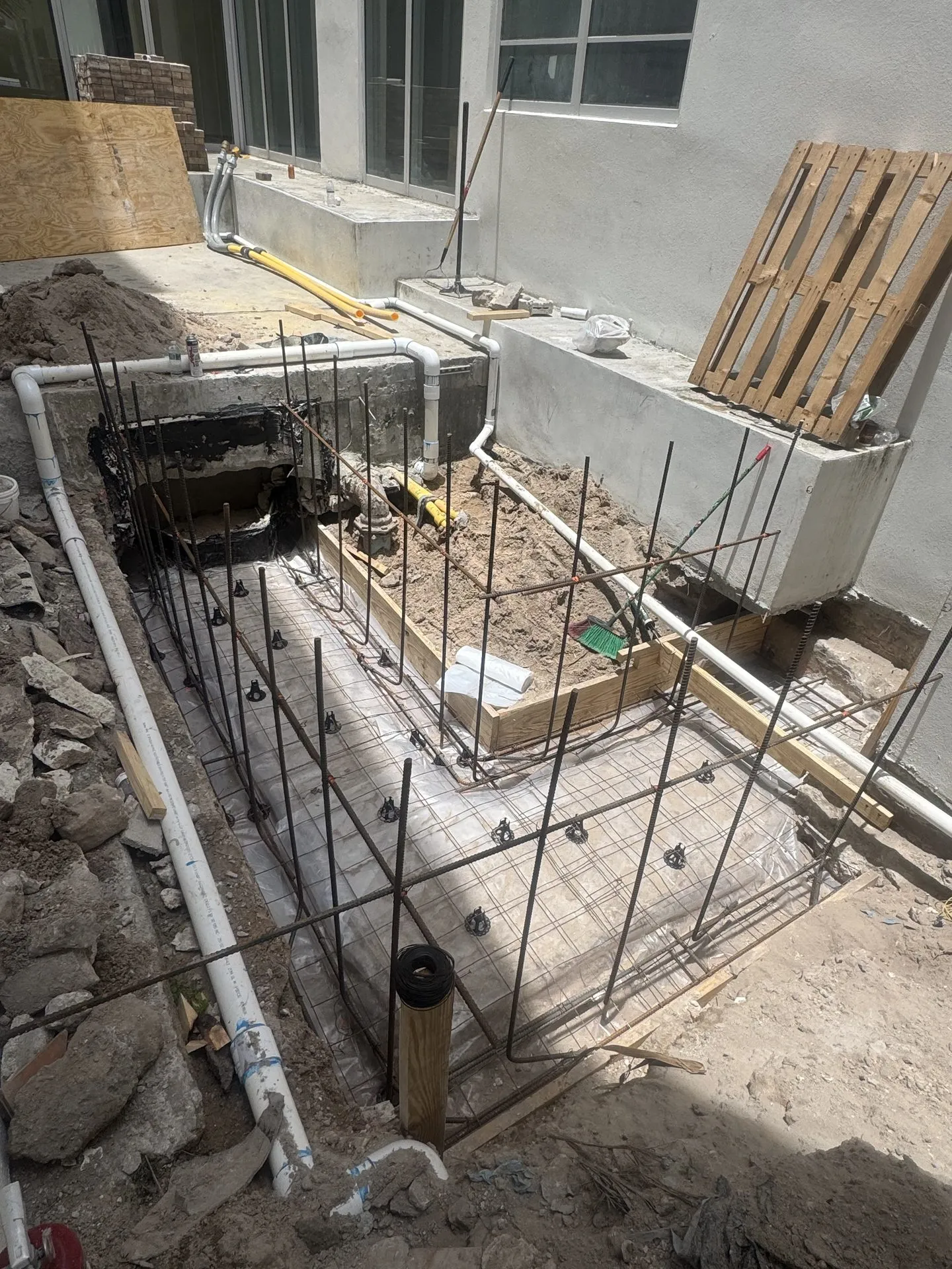 Rebar reinforcement and forms prepared for a concrete foundation beside a home