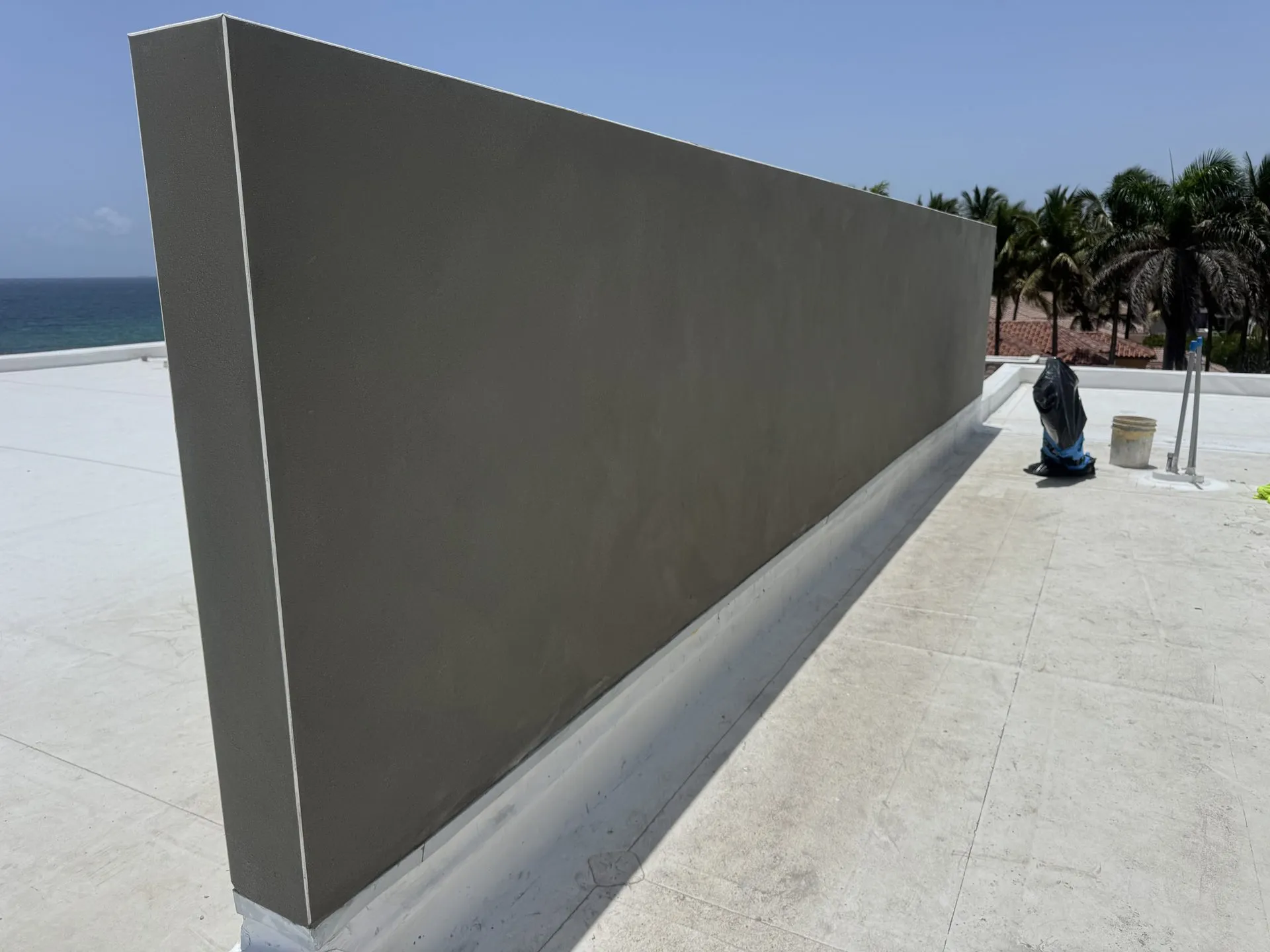 Finished gray stucco parapet wall on a rooftop overlooking the ocean