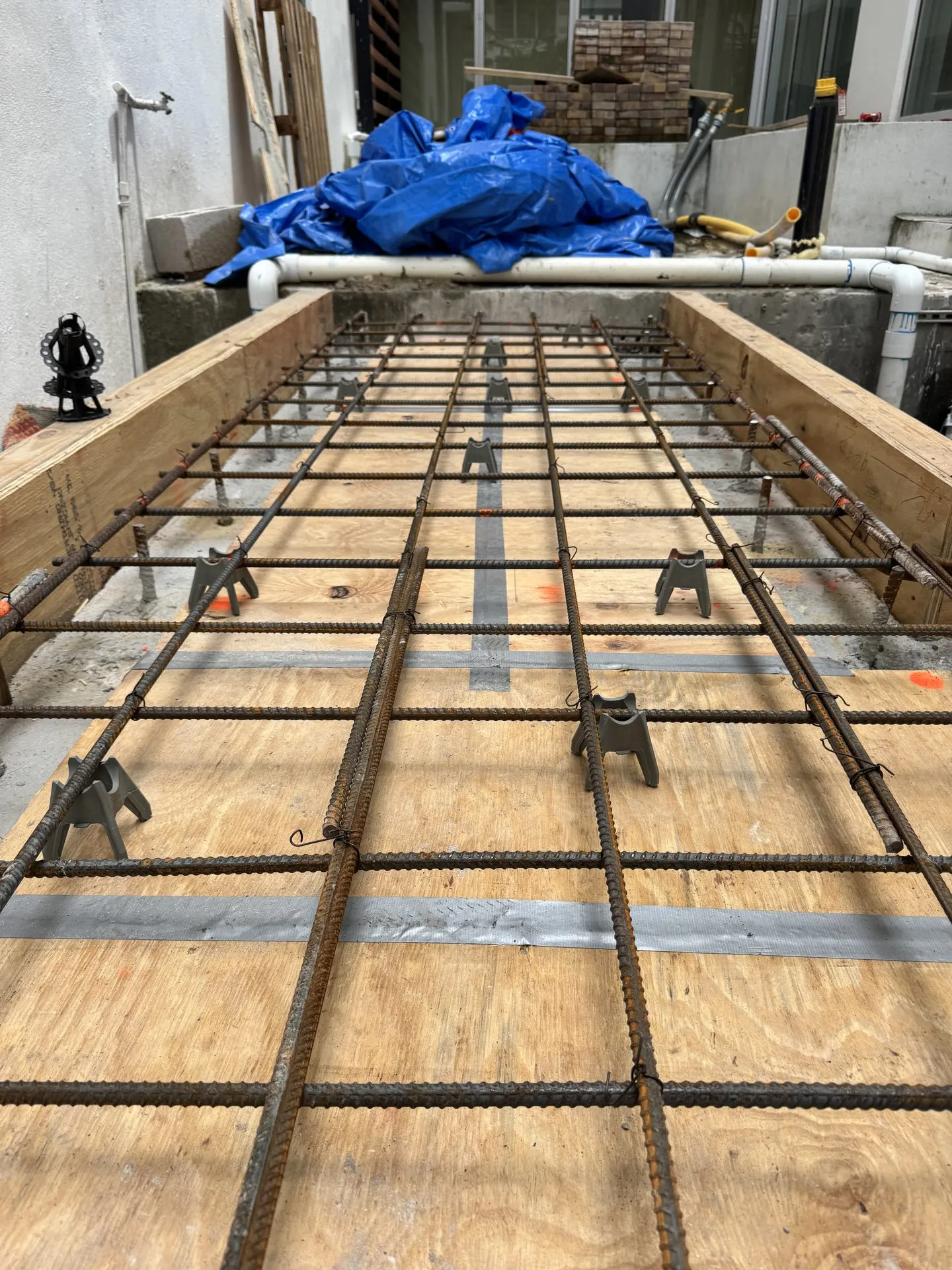 Rebar mat and chairs set on a plywood deck ready for a concrete pour