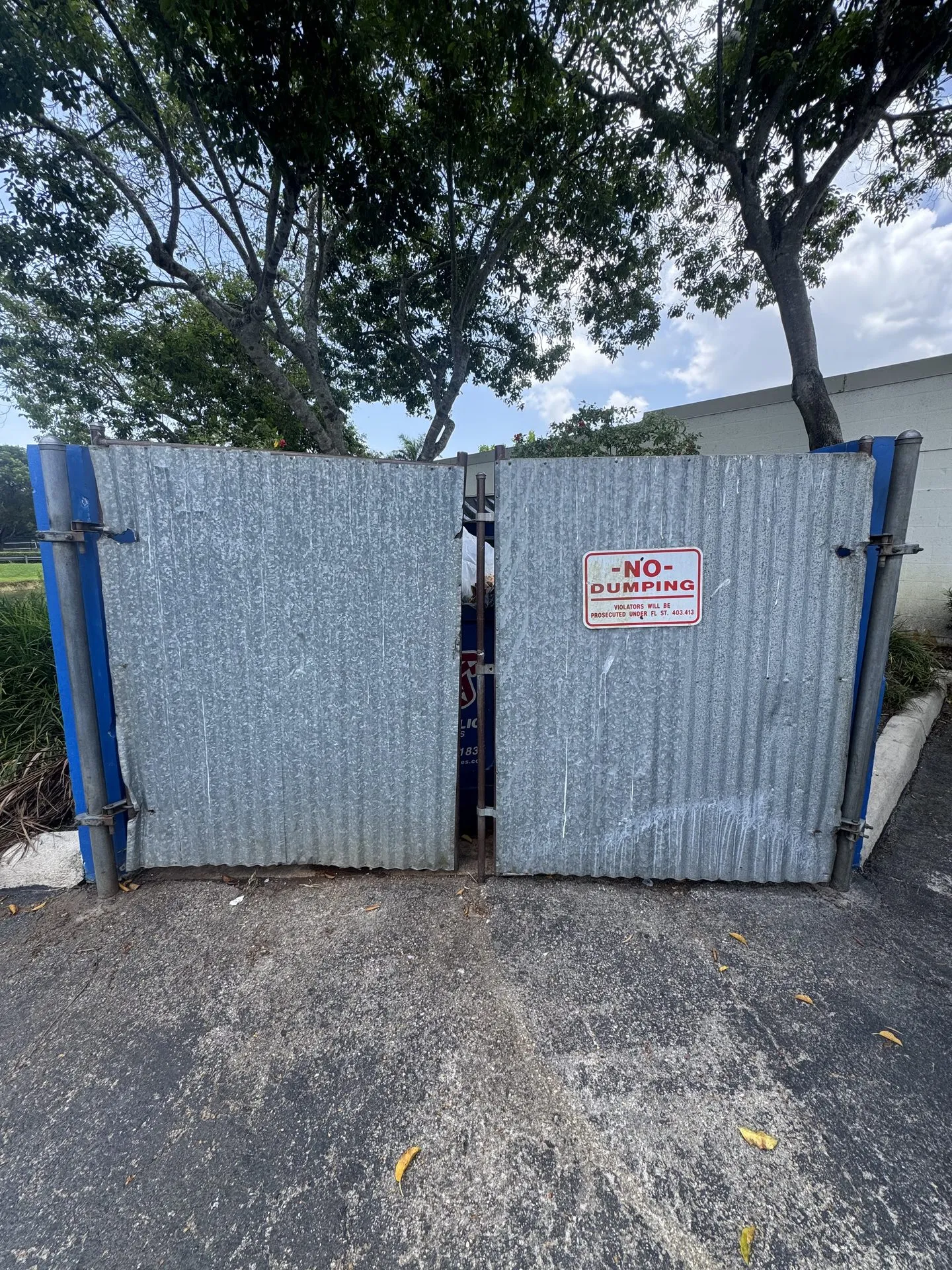 Galvanized steel dumpster enclosure gates with a no dumping sign