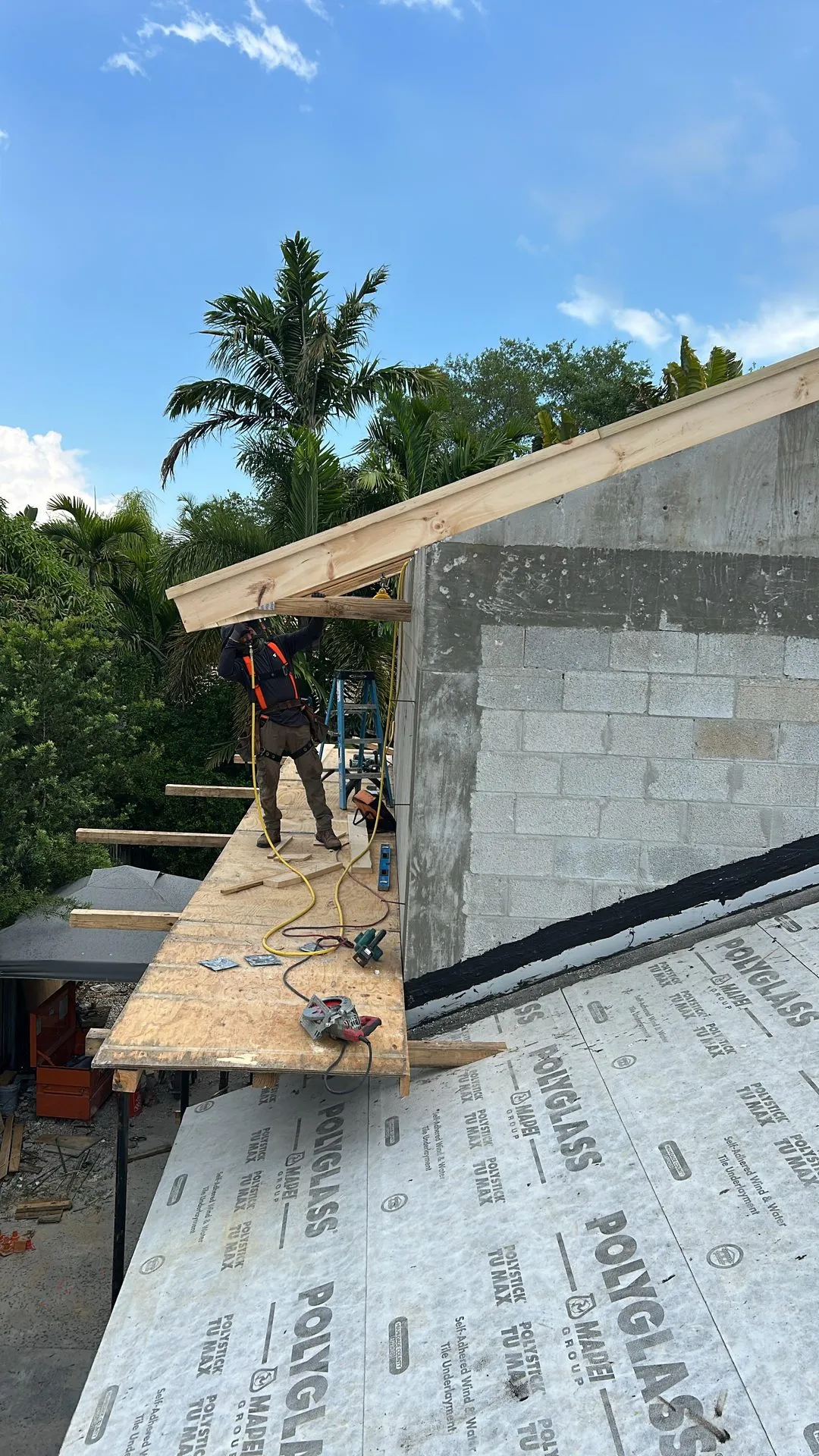Roof framing and underlayment beside a new concrete block wall