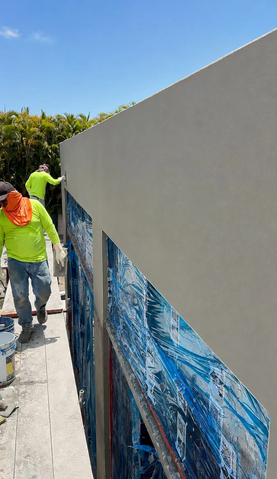Stucco crew applying exterior wall finish over a waterproofing membrane