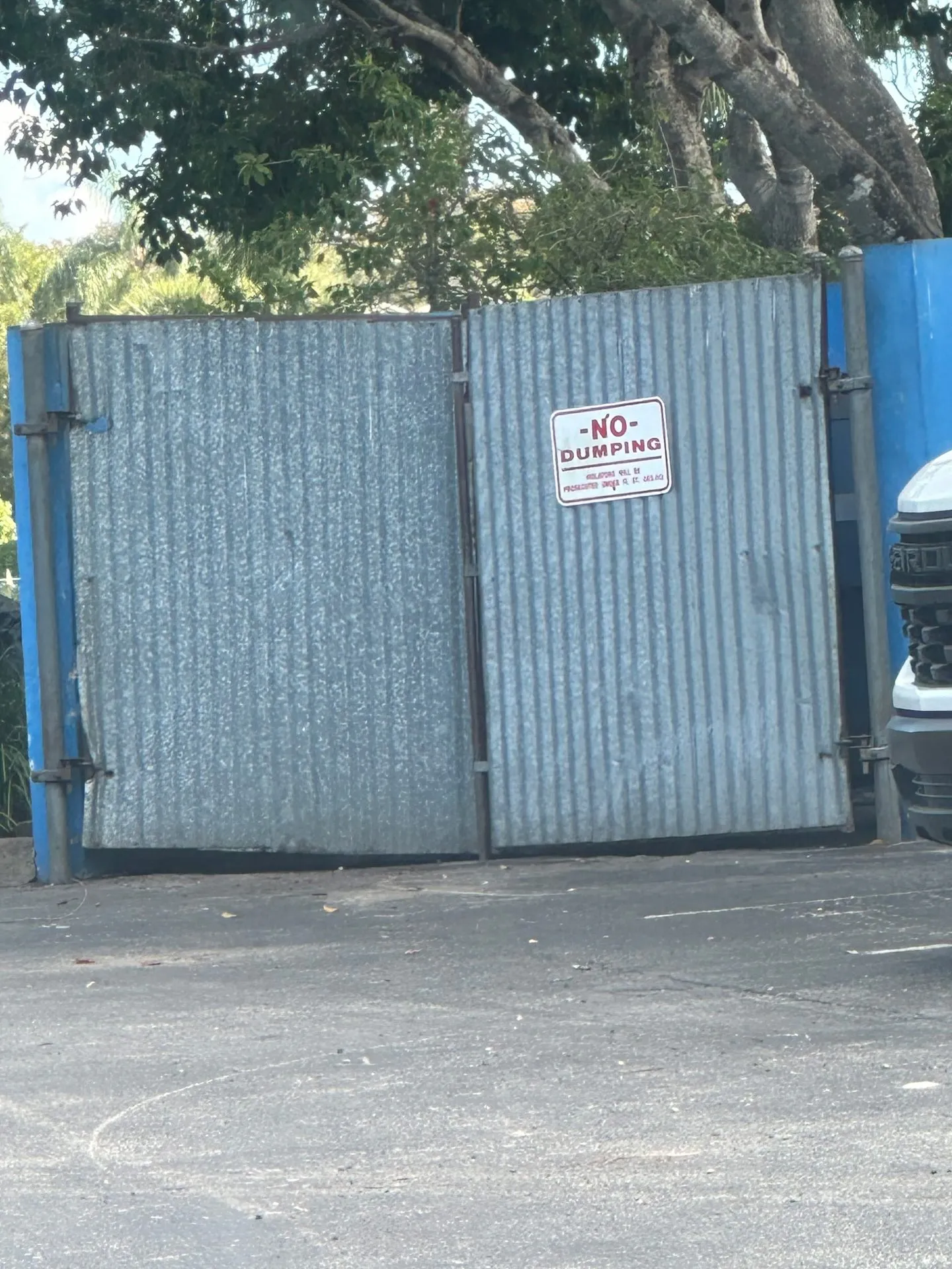 Galvanized steel dumpster enclosure gate in a commercial parking lot